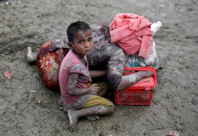 A Rohingya refugee girl sits next to her mother who rests after crossing the Bangladesh-Myanmar border, in Teknaf, Bangladesh. A Rohingya refugee girl sits next to her mother who rests after crossing the Bangladesh-Myanmar border, in Teknaf, Bangladesh.