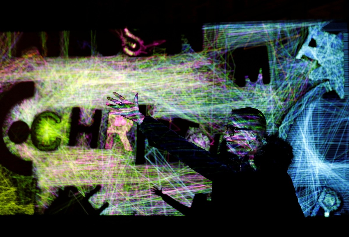 A woman gestures in front of the installation