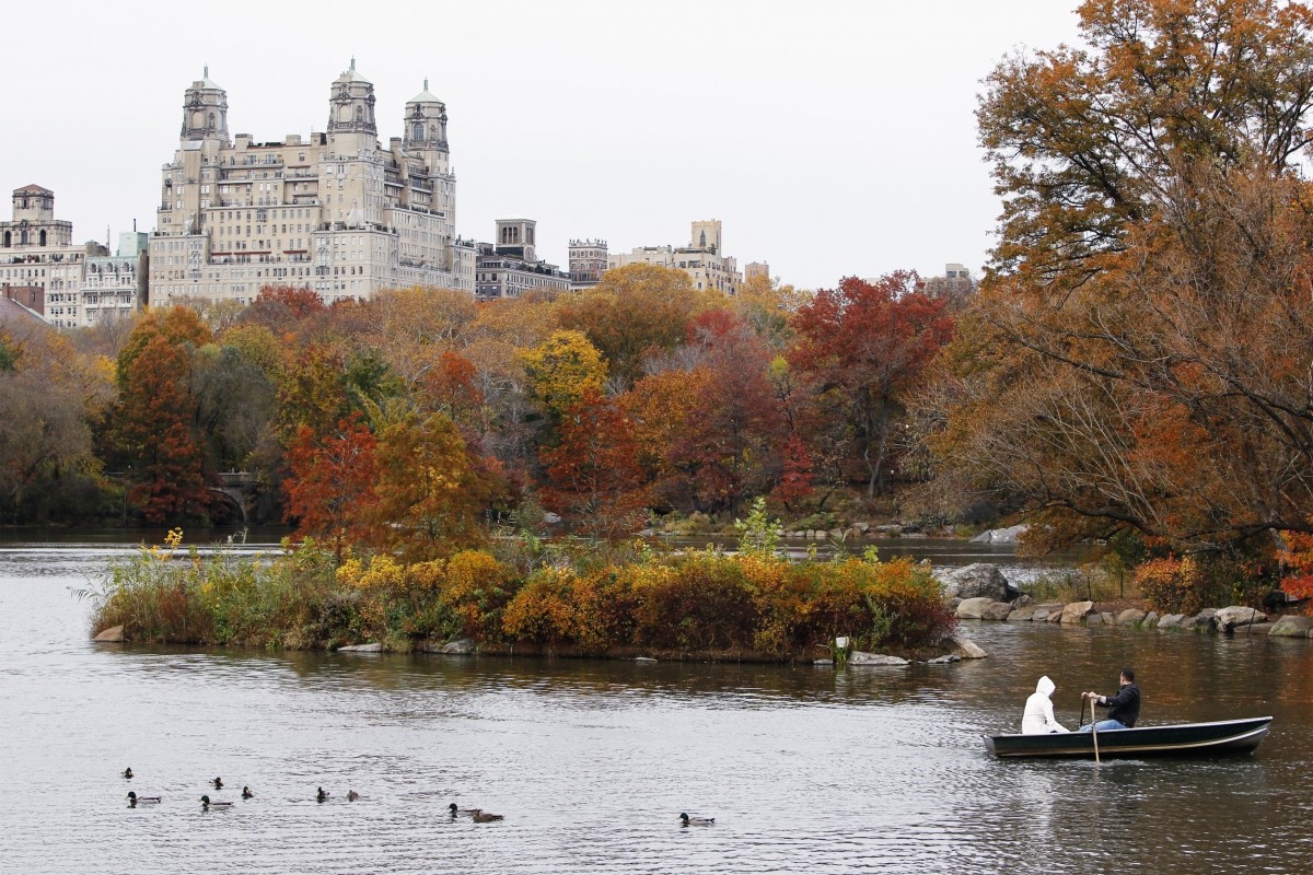 A couple rides in a boat amongst fall foliage in Central Park in New York Fall Foliage season