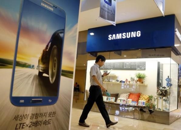 A man using his mobile phone walks past a Samsung Electronics shop in the company's main office building in central Seoul. IB Times