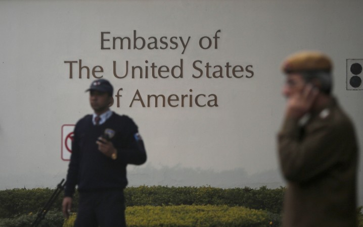 A U.S. embassy security guard (L) and an Indian policeman stand in front of the main gate of the embassy as the bulldozer (unseen) removes the security barriers, in New Delhi December 17, 2013. US embassy in India, h-1 b visa, donald trump buy american hire american, infosys h-1 b visa