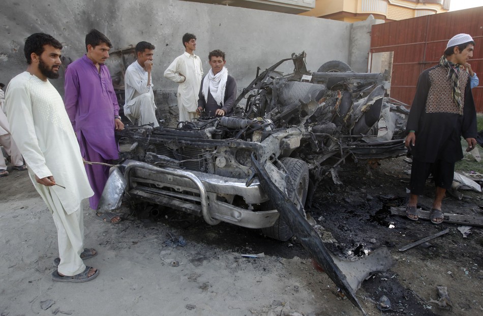 Afghan men stand around the wreckage of a car used by a suicide attacker in Jalalabad province April 15, 2012. Taliban Attack in Kabul