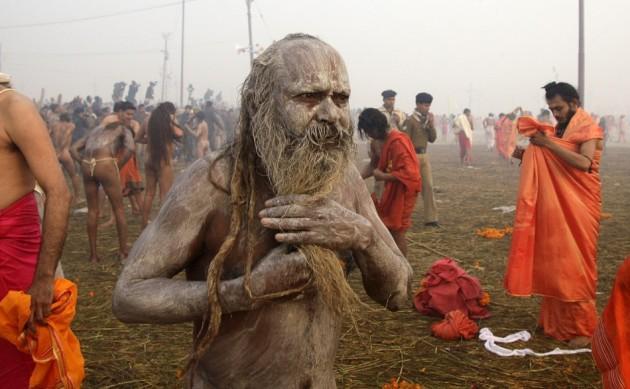 Sadhu or Hindu holy man applies ashes on his body after taking dip during first Kumbh Mela