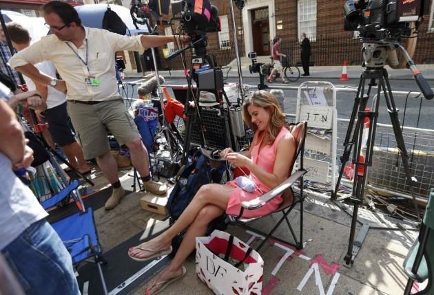 News presenter Natalie Morales, of NBC Today, knits baby booties in the media pen opposite the Lindo Wing of St Mary's Hospital, where Britain's Catherine, Duchess of Cambridge is due to give birth, in London Royal baby