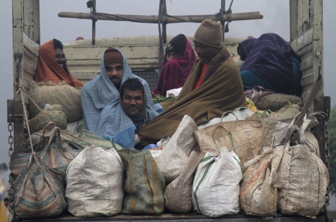 Vendors covered in blankets sit in the back of a supply truck after buying vegetables from a market on a cold winter morning in Kolkata Cold wave in north India