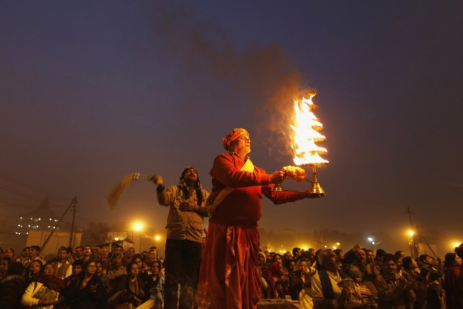 Hindu priest holds oil lamp as performs evening prayers near banks of river Ganges ahead of Kumbh Mela