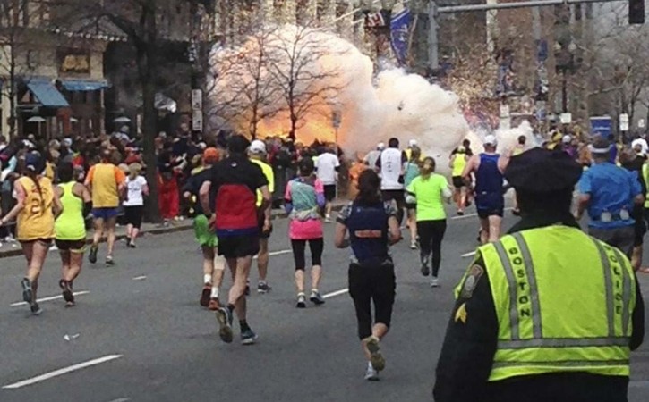Runners continue to run towards the finish line as an explosion erupts at the finish line of the Boston Marathon Boston Marathon