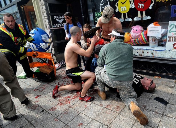 Bystanders tend to an injured man following explosions at the Boston Marathon finish area Boston Marathon