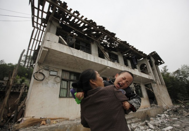 A boy cries as his mother holds him in front of their damaged house after a strong 6.6 magnitude earthquake at Longmen village, Lushan county in Ya'an, Sichuan province April 21, 2013.(Reuters) A boy cries as his mother holds him in front of their damaged house after a strong 6.6 magnitude earthquake at Longmen village, Lushan county in Ya'an, Sichuan province April 21, 2013.