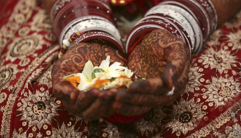 A bride holds flowers with her hands decorated with henna paste during her wedding ceremony in the western Indian city of Ahmedabad Image (representational image) Credit: REUTERS Indian Bride