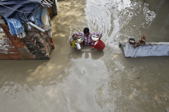 A resident carries his belongings through an alley flooded with the rising water level of river Yamuna after heavy monsoon rains in New Delhi (Reuters) A resident carries his belongings through an alley flooded with the rising water level of river Yamuna after heavy monsoon rains in New Delhi (Reuters)