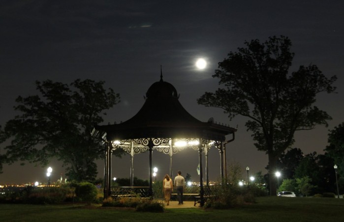 People walk through a gazebo as a full moon also referred to as a Supermoon 2013