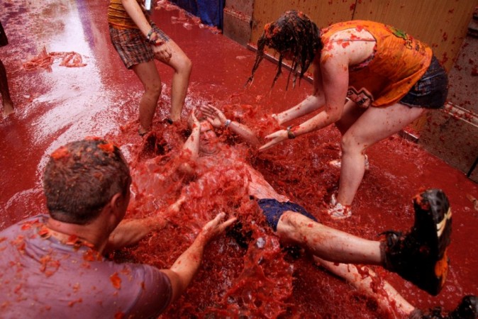 Revellers pour tomato pulp over another after the annual La Tomatina Festival 2013