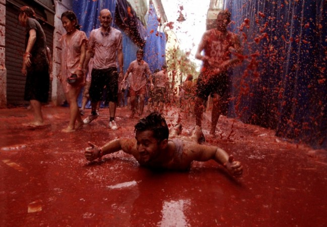 A reveller plays in tomato pulp after the annual La Tomatina Festival 2013