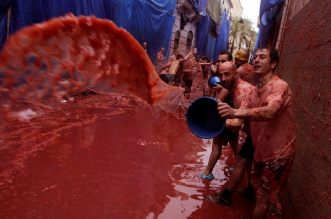 A reveller pours tomato pulp over others after the annual La Tomatina Festival 2013
