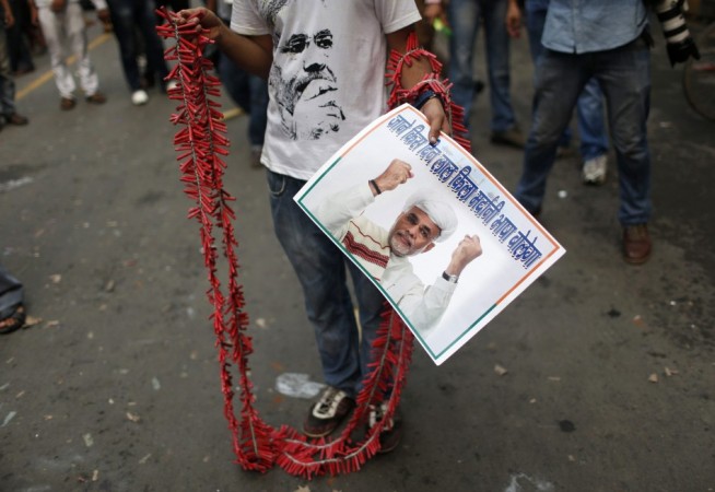 A BJP supporter holds firecrackers and a poster of Narendra Modi during celebrations in New Delhi BJP supporter