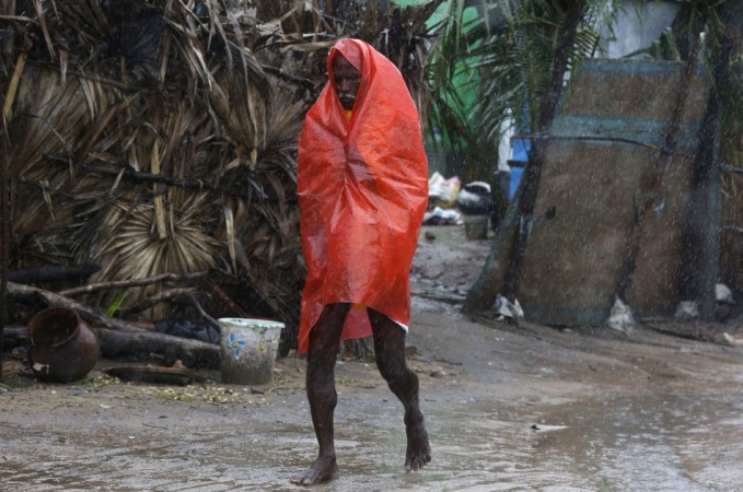 A man covers himself with a plastic sheet during heavy rain brought by Cyclone Phailin as he moves towards a safer place at the village Donkuru in Srikakulam district in Andhra Pradesh Cyclone Phailin