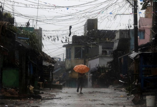 A man tries to cover himself with an umbrella during heavy rain brought by Cyclone Phailin as he moves towards a safer place at the village Donkuru in Srikakulam district in Andhra Pradesh Cyclone Phailin
