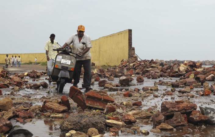 People walk among debris from a broken wall after it was damaged by a wave brought by Cyclone Phailin in Visakhapatnam district Cyclone Phailin