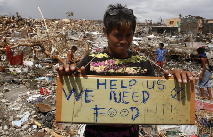 A typhoon victim holds a placard asking for food in the aftermath of super typhoon Haiyan in Tanauan Typhoon Haiyan