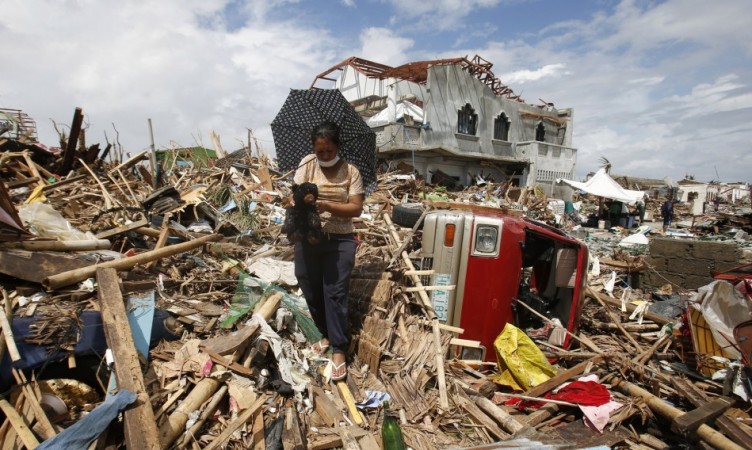 A woman retrieves a teddy bear amongst the debris in the aftermath of super typhoon Haiyan in Tanauan Typhoon Haiyan