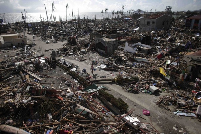 Residents walk in a village among houses destroyed by super Typhoon Haiyan in Tanauan Typhoon Haiyan