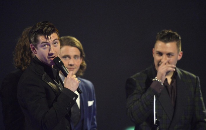 Alex Turner of the Arctic Monkeys talks near Matt Helders after being presented with the British Album award at the BRIT Awards in London Arctic Monkeys