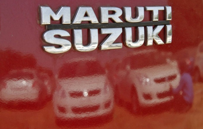 A worker cleans a Maruti Suzuki Swift Dzire car as he is reflected in a car at the company's stock yard at Sanand in Gujarat