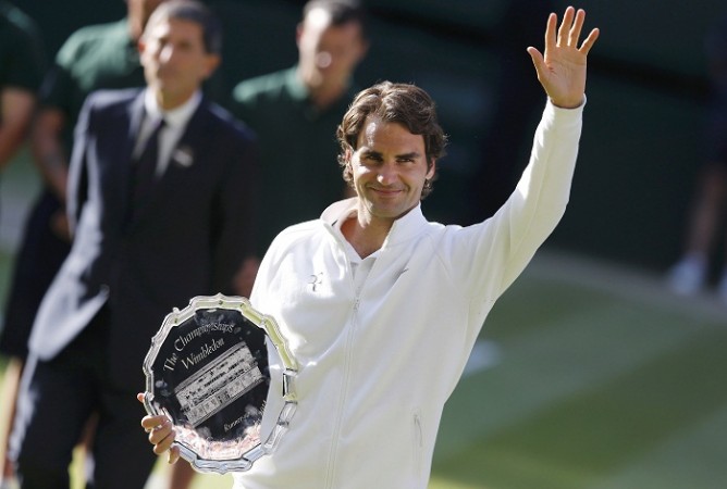 Roger Federer waves while holding the runner-up's trophy after being defeated by Novak Djokovic. Roger Federer