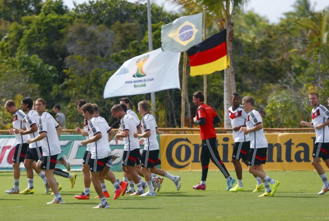 Germany's national soccer team runs past a German and Brazil national flag during a training session in the village of Santo Andre Germany