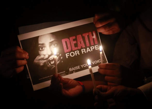 People hold a placard during a candlelight vigil in support of 'Nirbhaya'