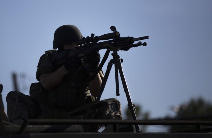 A riot police officer aims his weapon while demonstrators protest the shooting death of teenager Michael Brown, in Ferguson, Missouri August 13, 2014.
