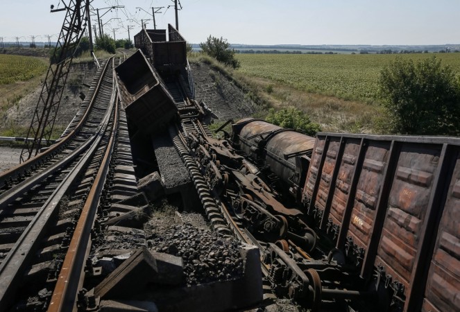 Train wagons are seen on the destroyed railway bridge which collapsed during the fighting between the Ukrainian army and pro-Russian separatists, over a main road leading to the eastern Ukrainian city of Donetsk, near the village of Novobakhmutivka, north of Donetsk city, August 27, 2014. Ukraine Crisis