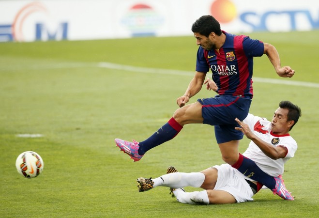 Barcelona's Luis Suarez (L) shoots and scores a goal against Indonesia U19 player Hansamu Yama during a friendly soccer match. Suarez