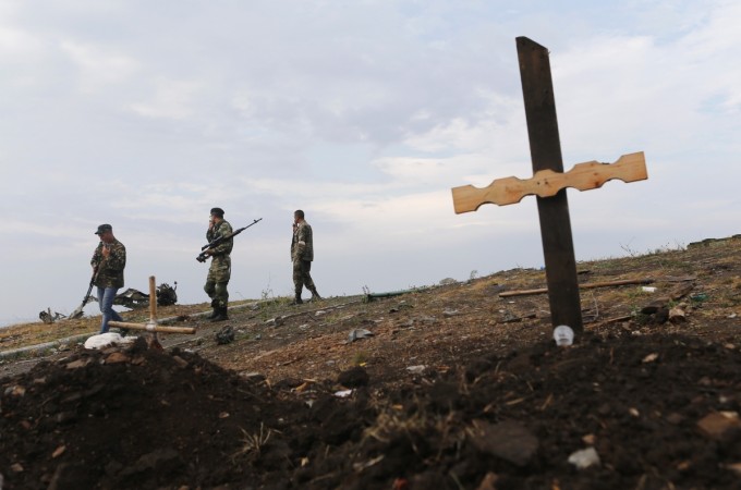 Pro-Russian separatists walk past an unmarked grave at Savur-Mohyla, a hill east of the city of Donetsk, August 28, 2014. Ukrainian President Petro Poroshenko said on Thursday that Russian forces had entered his country and the military conflict was worsening after Russian-backed separatists swept into a key town in the east. Donetsk Ukraine mass grave
