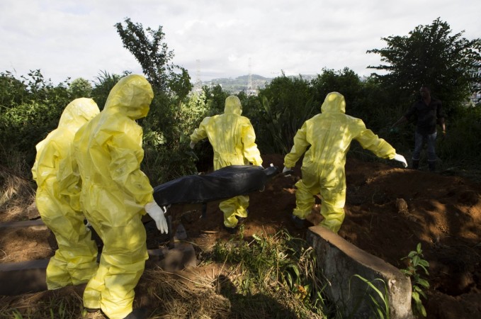 A burial team, wearing protective clothing, take away the body of a person suspected to have died of Ebola. Ebola victims