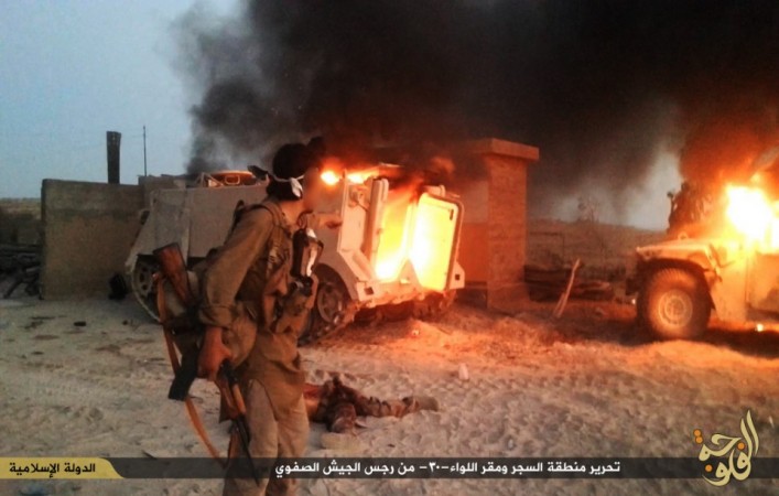 An ISIS fighter looks at a destroyed M113 armoured personnel carrier An ISIS fighter looks at a destroyed M113 armored personnel carrier