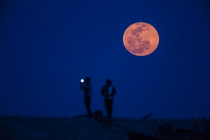 Observers take picture during a blood moon rising in Shanghai.