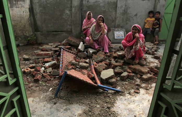 Villagers sit on the debris of their house.