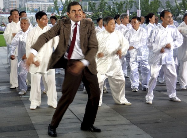 British actor Rowan Atkinson (front), dressed as his popular television character Mr. Bean, dances with Chinese performers during the filming of a promotional video in Shanghai August 20, 2014. Rowan Atkinson