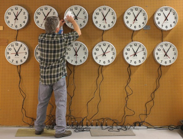 Scott Gow cleans the faces of wall clocks being tested before going to a Capital Grill restaurant at the Electric Time Company in Medfield, Massachusetts November 1, 2013. aylight saving time
