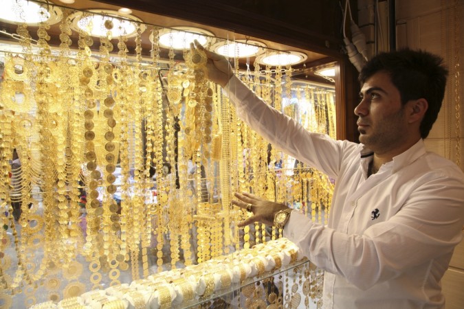 A goldsmith shop owner displays gold pieces at a gold market. Gold