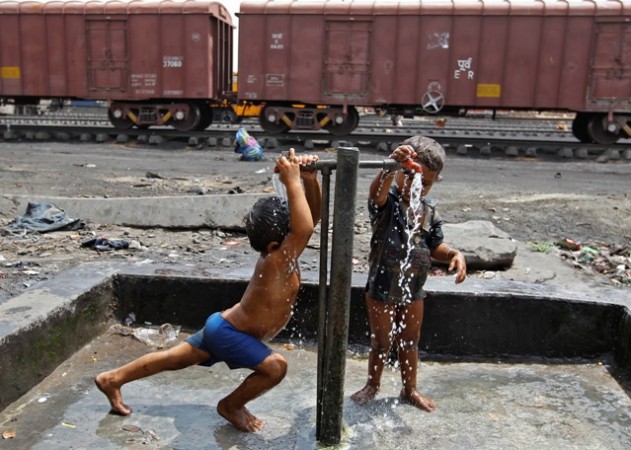 Children of railway workers bathe under water taps installed at a railway goods yard, in Ahmedabad on 8 July 2014. Train labourers