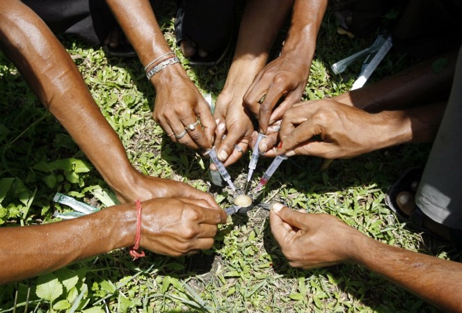 Drug users fill their syringes with a mix of brown sugar and Fortwin (addictive drug) before injecting themselves at a roadside in the northeastern Indian city of Siliguri June 26, 2008. Drug abuse