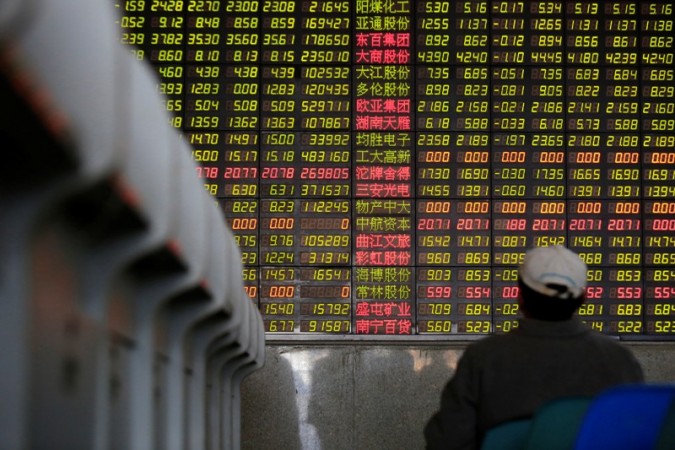An investor looks at an electronic board showing stock information at a brokerage in Shanghai. China Stocks