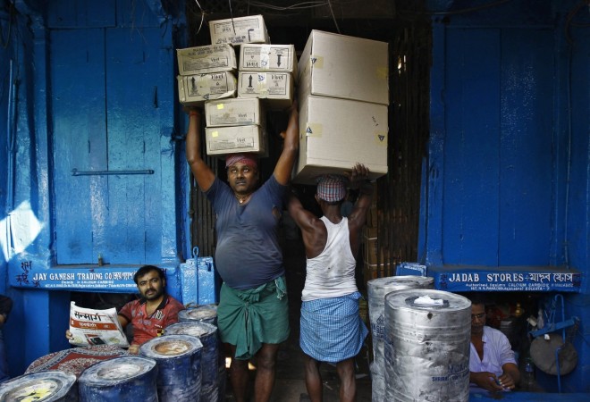 Labourers carry grocery items at a wholesale market in Kolkata November 14, 2014. India's inflation dropped to a new multi-year low in October, helped by slower annual rises in food and fuel prices, intensifying pressure on the central bank to cut interest rates to encourage spending and investment needed to boost growth. Laborers at work