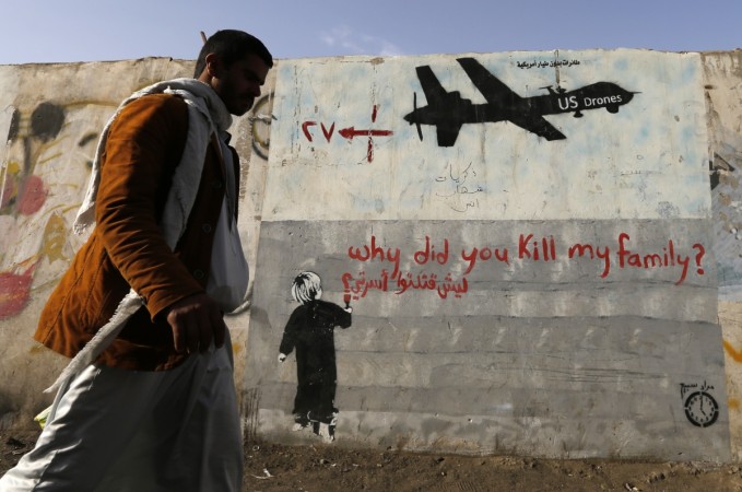 A man walks past a graffiti, denouncing strikes by U.S. drones in Yemen. Taliban official killed by US drone
