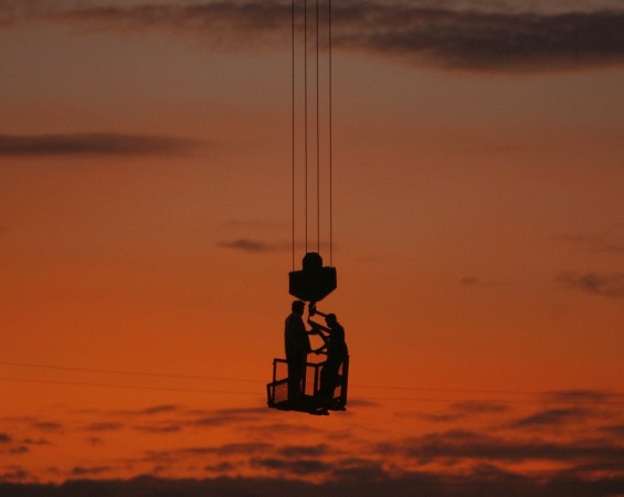 Labourers stand on a winch of a crane at a construction site on the outskirts of New Delhi Indian laborers at a construction site