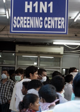 People wearing masks wait in a queue for a H1N1 flu screening at a hospital in New Delhi August 11, 2009. swine flu