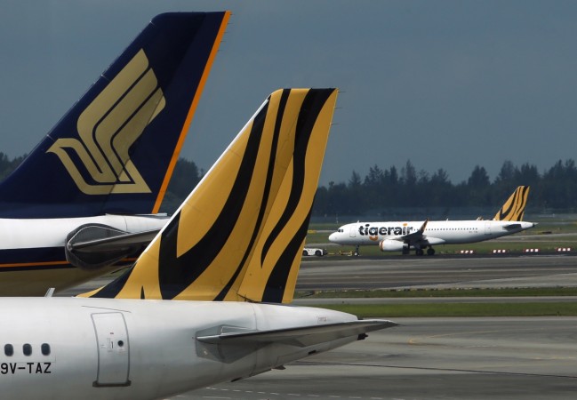 A Tiger Airways plane is towed on the runway past Singapore Airlines and Tiger Airways planes sitting on the tarmac at Changi Airport in Singapore. Tigerair